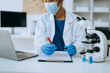 Modern medical research laboratory. African female scientist working with micro pipettes analyzing...