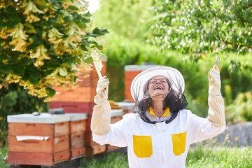Cheerful female apiarist holding hive fork and brush