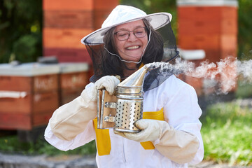 Happy senior female apiarist holding smokepot