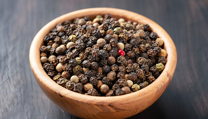 Peppercorns in a wooden bowl on a dark background