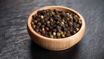 Peppercorns in a wooden bowl on a dark background