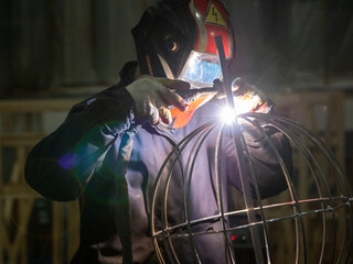 Worker welding metal structures at construction site in plant