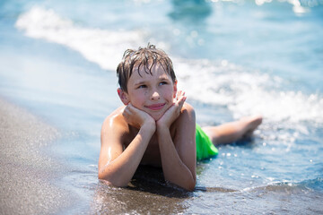 Happy boy is resting by the sea, playing with the waves. Child on vacation at the seaside.