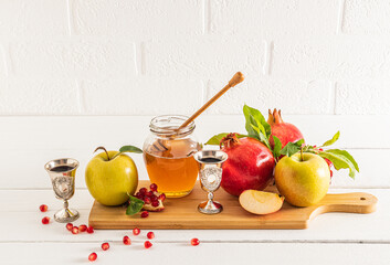 A jar of honey and spindle on a wooden board with ripe fruits, pomegranates and apples. traditional...