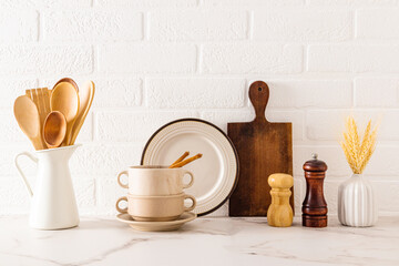 Front view of a kitchen marble countertop with a set of kitchen utensils and utensils against a white brick wall. Cozy kitchen.