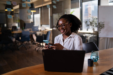 Black businesswoman working on laptop. Portrait of beautiful businesswoman in the office. Woman using the phone..