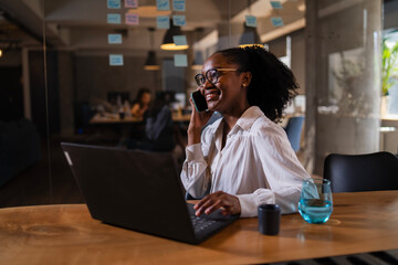 Black businesswoman working on laptop. Portrait of beautiful businesswoman in the office. Woman taking to the phone..