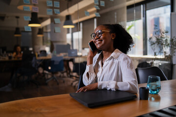 Black businesswoman working on laptop. Portrait of beautiful businesswoman in the office. Woman taking to the phone..