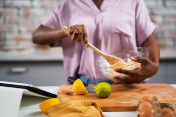 Young African woman in kitchen. Beautiful woman having fun while making dough