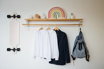 White shirts and a blue jacket hanging on a wooden shelf in the teen room