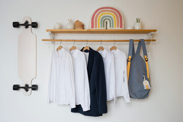 White shirts and a blue jacket hanging on a wooden shelf in the teen room