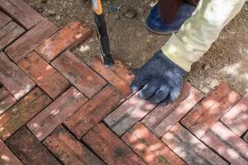 worker laying red brick  pathway around the house