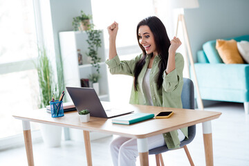 Portrait of delighted cheerful girl sit table raise fists shout yes hooray wireless netbook macbook...