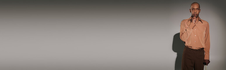 real people, bold african american man with myasthenia gravis syndrome standing with walking cane on grey background, dark skinned person in shirt, diversity and inclusion, looking at camera, banner