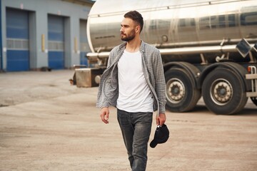 Against vehicle. Young truck driver in casual clothes