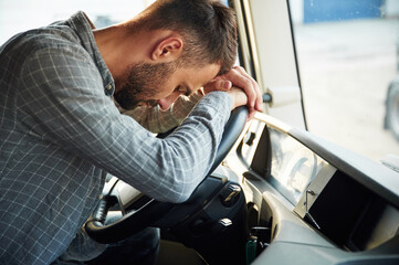 Sitting inside, tired. Young truck driver in casual clothes