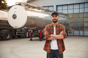 Standing with arms crossed. Young truck driver in casual clothes