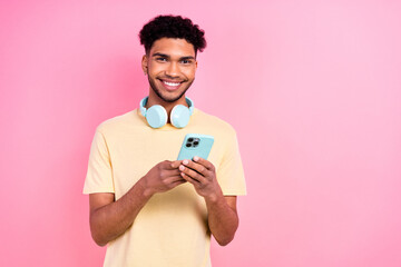 Photo of smart youngster guy with earrings dressed yellow stylish t-shirt typing email on smartphone isolated on pink color background