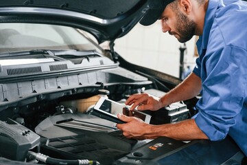 Fototapeta na wymiar Using tablet. Auto mechanic working in garage. Repair service