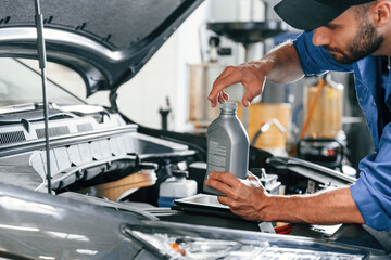 Oil can in hands. Auto mechanic working in garage. Repair service