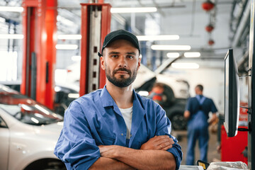 Standing with arms crossed. Auto mechanic working in garage. Repair service