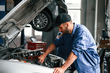 Adjusting the screws. Auto mechanic working in garage. Repair service