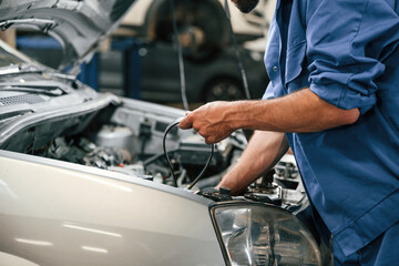 Adjusts the cable. Auto mechanic working in garage. Repair service