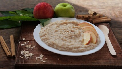 Plate of oatmeal porridge with red apple slices and cinnamon. Close up.