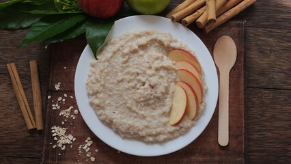 Plate of oatmeal porridge with red apple slices and cinnamon. Close up.