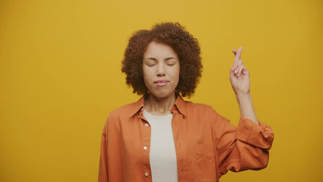 Woman Raising Arm with Fingers Crossed and Eyes Closed
