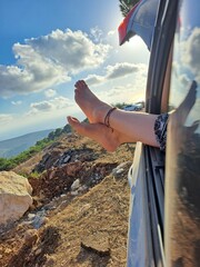 Woman's feet hanging over the caravan window in the nature
