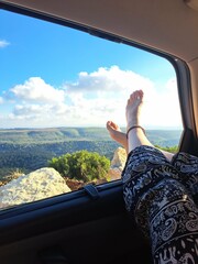 Woman's feet hanging over the caravan window in the nature