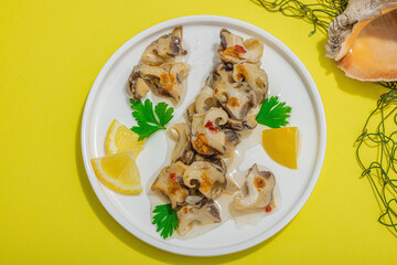 Pickled rapan meat with oil, spices and greens. Healthy seafood rich of omega