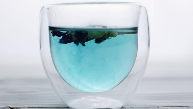Pea tea "Blue Butterfly" from the flowers of the clitoris is brewed in a transparent glass. Soft focus