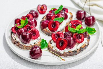 Fresh bread sandwiches with sweet cherry, cream cheese and mint leaves. Morning breakfast concept