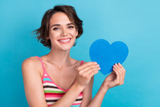 Portrait picture photo of young lovely woman bob hair holding blue big postcard heart symbol romantic isolated on cyan color background