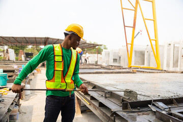 African american mason worker pouring the ready-mixed concrete at Heavy Industry Manufacturing...