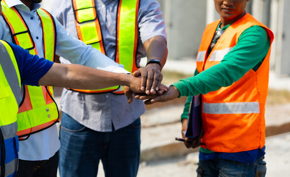 diverse construction engineering people putting hands together. Unity and teamwork concept. Asian and african american worker at factory