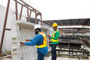 professional engineer African American man using measure tape and working at precast concrete wall factory. Yellow tape measure construction tools. Heavy Industry Manufacturing Factory