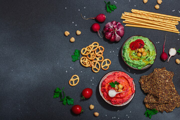 Various hummus dips, fresh vegetables and herbs. Crispy bread snacks, modern vegan healthy food