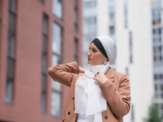 Young woman dressed in hijab and business suit walking outdoors. 