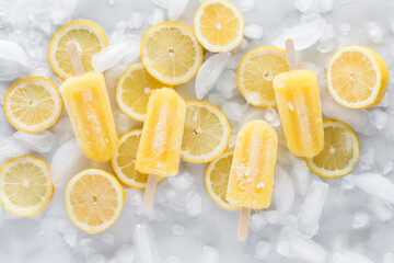 Lemonade ice pops on a bed of lemon slices with ice cubes.
