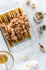 Chicken skewers marinading on bamboo skewers in a glass dish.