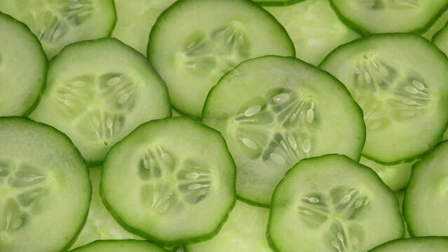 Top view fresh cucumber cut into slices rotate. Background of chopped cucumber slices for cooking show, restaurant, cafe, fast food. Moisturizing the skin and smoothing wrinkles