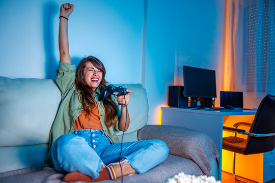 Woman playing video games at home celebrating after winning