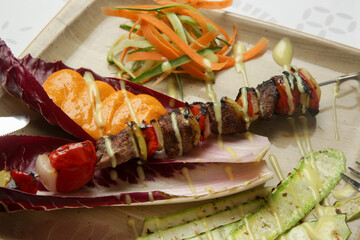 Greek souvlaki skewers served on the plate with vegetables in the restaurant	
