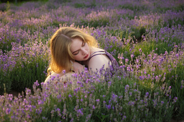 beautiful blonde girl with long hair on a lavender field in the evening - 625566827