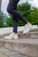 White sneakers with studded soles on female legs in black jeans