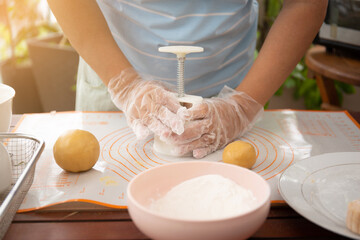 Female baker pressing raw dough bun with mold to make beautiful mooncake. Mooncake making process