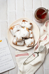 Fresh beignets come out of the fryer, topped with powdered sugar, ready to eat.